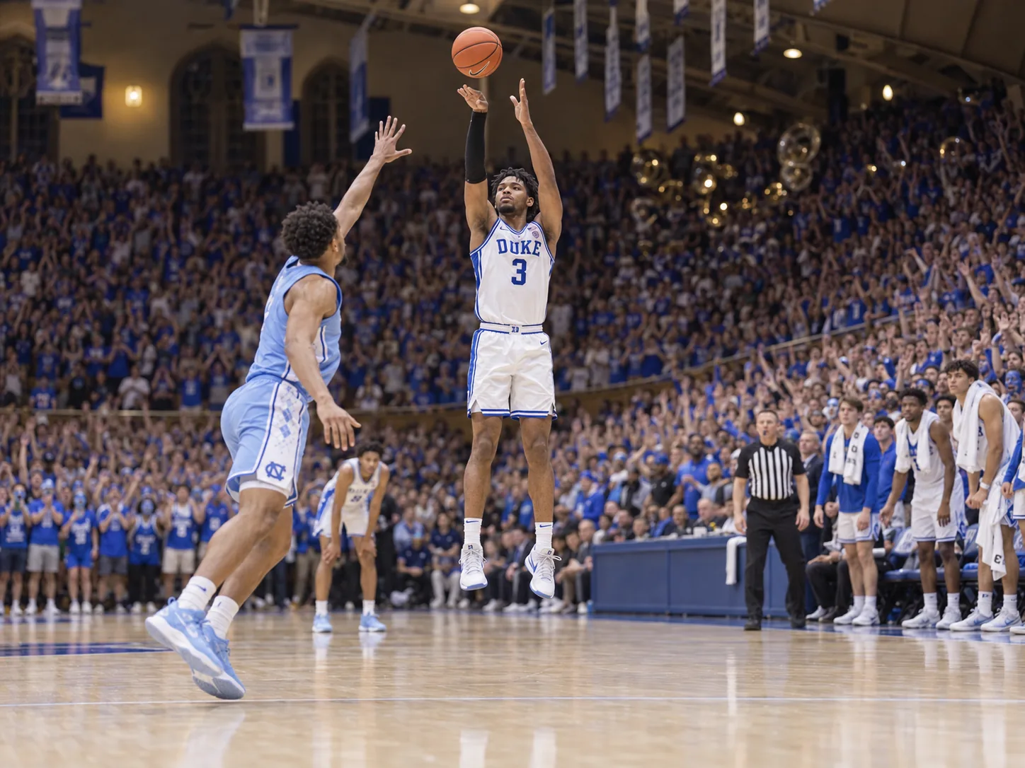 A Duke college basketball player in a white number 3 home jersey rises for a jump shot in a packed Cameron Indoor Stadium, the ball just off his fingertips and his eyes on the rim, as a North Carolina defender in light blue closes out too late and the student section shouts behind him.